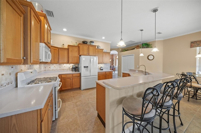 kitchen with an island with sink, white appliances, a breakfast bar area, pendant lighting, and ornamental molding