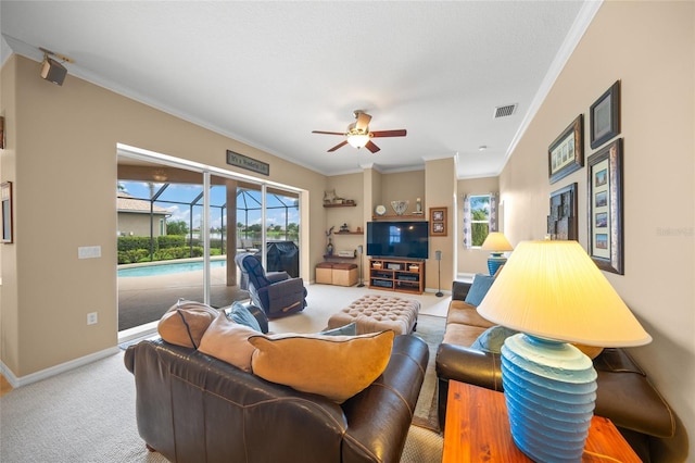 living room with carpet floors, ornamental molding, and ceiling fan