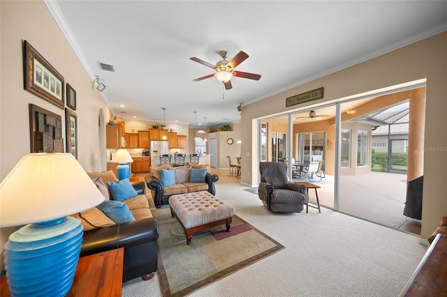 living room with ceiling fan, light colored carpet, and crown molding