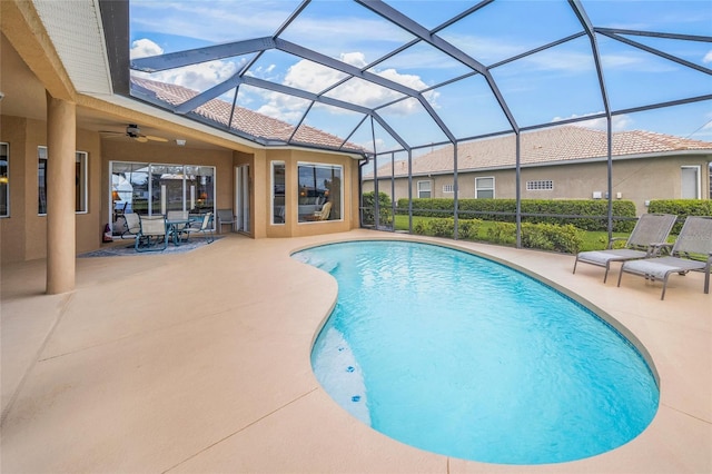 view of swimming pool featuring glass enclosure, ceiling fan, and a patio