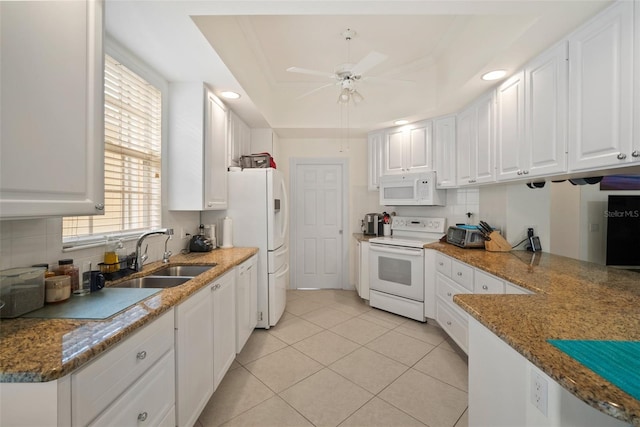 kitchen with white appliances, a raised ceiling, sink, light tile patterned floors, and white cabinetry