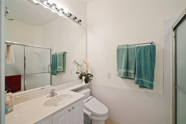 bathroom with vanity, toilet, a shower with shower door, and tile walls