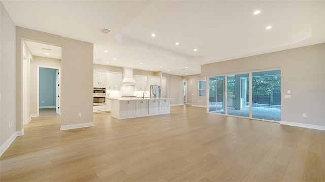 unfurnished living room with sink and light hardwood / wood-style floors