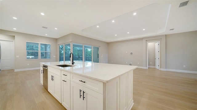 kitchen featuring an island with sink, light wood-type flooring, light stone countertops, sink, and dishwasher