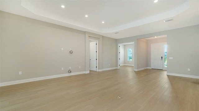 spare room featuring a raised ceiling and light hardwood / wood-style floors