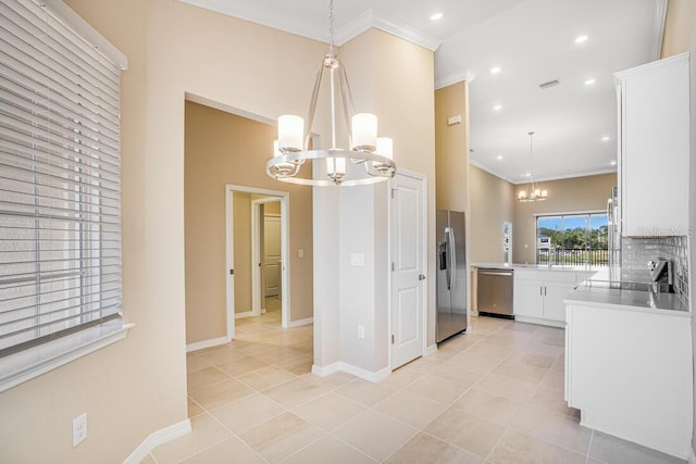 kitchen featuring an inviting chandelier, white cabinets, crown molding, appliances with stainless steel finishes, and decorative light fixtures