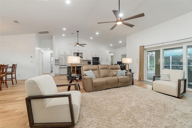 living room with ceiling fan, light hardwood / wood-style flooring, and vaulted ceiling