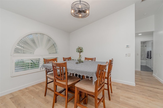 dining room featuring light wood-type flooring, lofted ceiling, and a chandelier