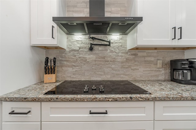 kitchen with black electric cooktop, white cabinetry, backsplash, light stone countertops, and ventilation hood