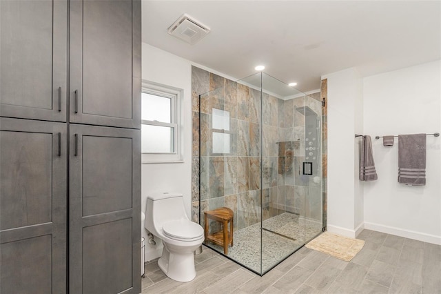 bathroom with a shower with door and toilet