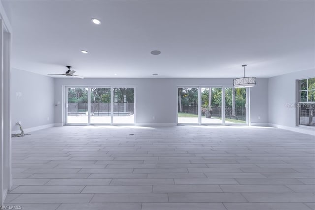 empty room with ceiling fan and a wealth of natural light