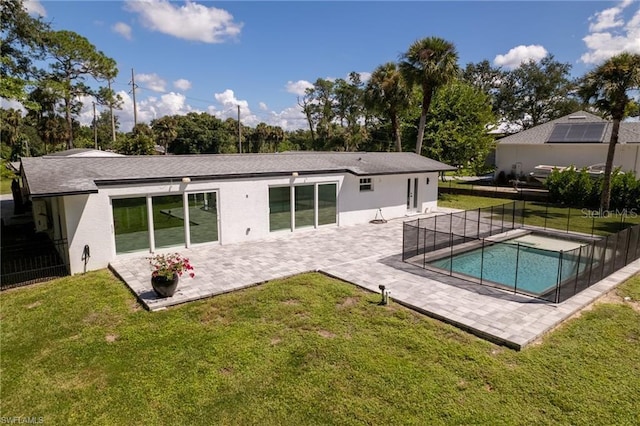 rear view of property featuring a yard, a fenced in pool, and a patio area