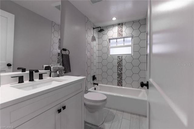 full bathroom featuring tiled shower / bath combo, vanity, and toilet