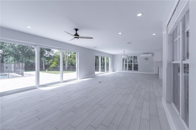 unfurnished living room with ceiling fan, light hardwood / wood-style flooring, and a wall mounted air conditioner