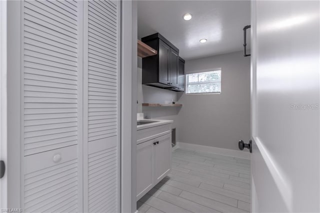 laundry area with light hardwood / wood-style floors and cabinets