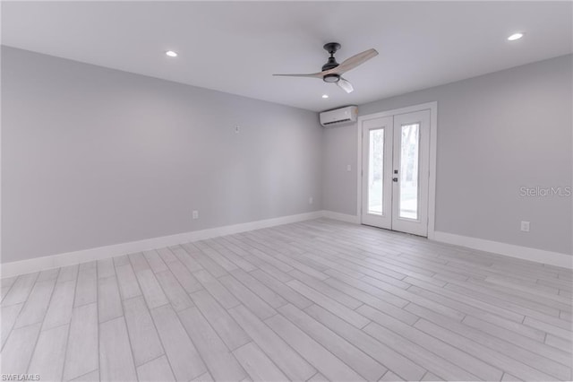 empty room featuring ceiling fan, light hardwood / wood-style flooring, french doors, and a wall mounted air conditioner