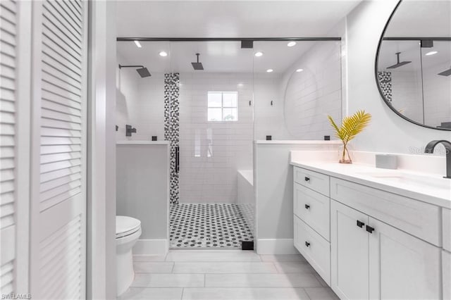 bathroom with vanity, tile patterned flooring, toilet, and tiled shower