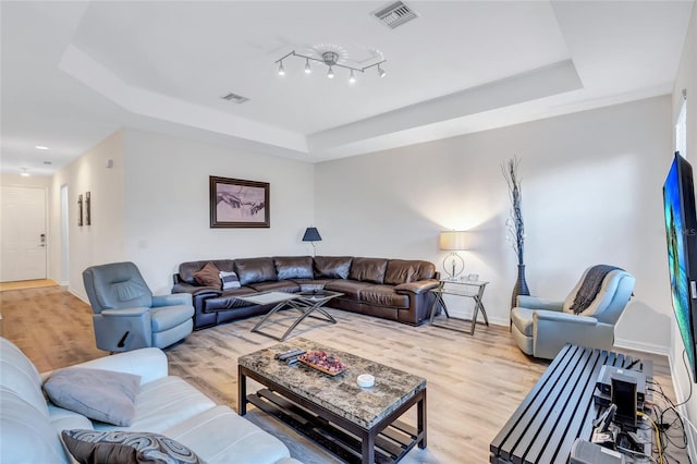 living room featuring light hardwood / wood-style flooring and a raised ceiling