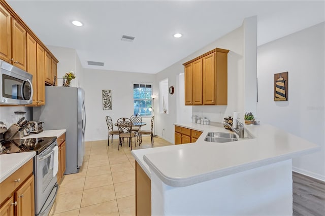 kitchen featuring kitchen peninsula, sink, light tile patterned floors, and stainless steel appliances