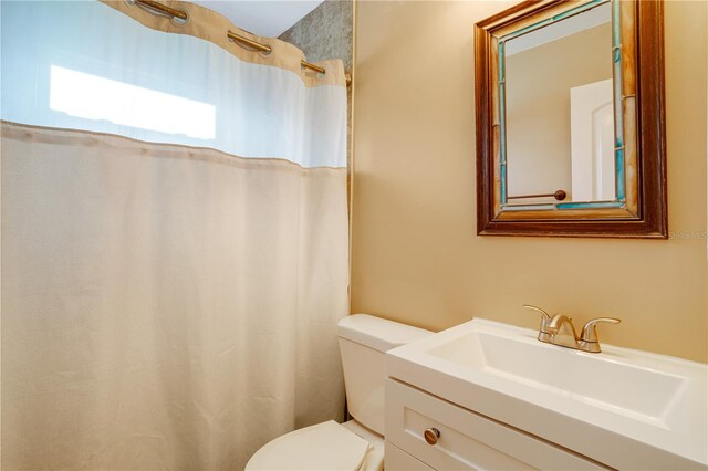 bathroom featuring walk in shower, vanity, and toilet