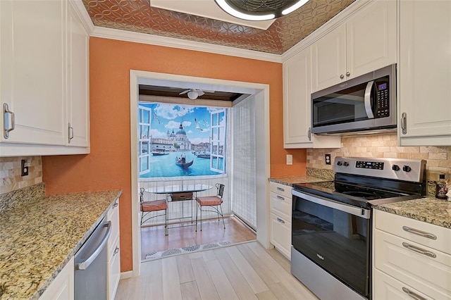 1026 Bird Bay Way Unit 276, Venice, FL 34285 - kitchen featuring stainless steel appliances, white cabinetry, backsplash, light stone counters, and light wood-style floors