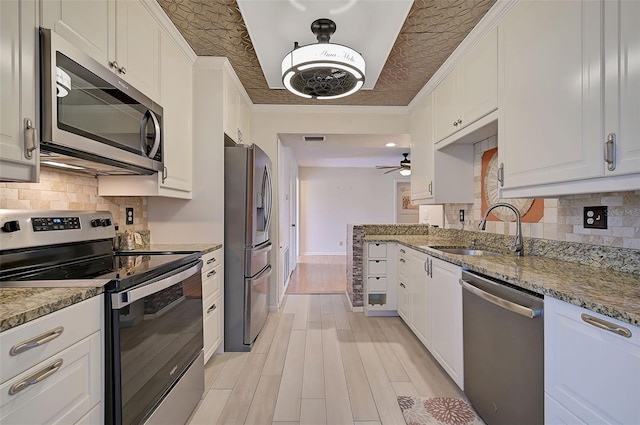 1026 Bird Bay Way Unit 276, Venice, FL 34285 - kitchen featuring appliances with stainless steel finishes, a sink, white cabinets, light wood-style flooring, and decorative backsplash