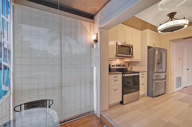 1026 Bird Bay Way Unit 276, Venice, FL 34285 - kitchen with appliances with stainless steel finishes, light wood-style floors, white cabinets, and tasteful backsplash