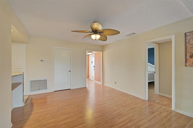 1026 Bird Bay Way Unit 276, Venice, FL 34285 - unfurnished living room featuring light wood-style floors, ceiling fan, baseboards, a textured ceiling, and radiator