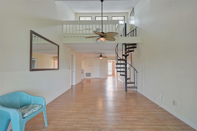 1026 Bird Bay Way Unit 276, Venice, FL 34285 - entrance foyer featuring a ceiling fan, stairs, light wood-style flooring, a towering ceiling, and baseboards