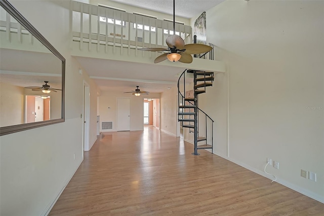 1026 Bird Bay Way Unit 276, Venice, FL 34285 - unfurnished living room featuring stairs, ceiling fan, wood finished floors, baseboards, and a high ceiling