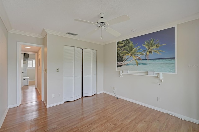 1026 Bird Bay Way Unit 276, Venice, FL 34285 - unfurnished bedroom with wood finished floors, crown molding, a closet, baseboards, and a ceiling fan