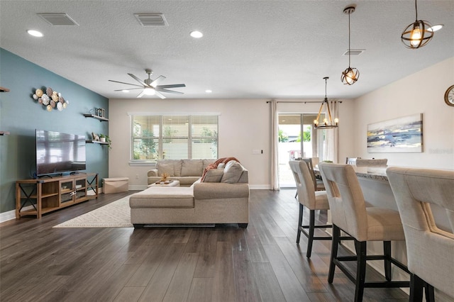 living room with ceiling fan, a textured ceiling, dark wood-type flooring, and a healthy amount of sunlight