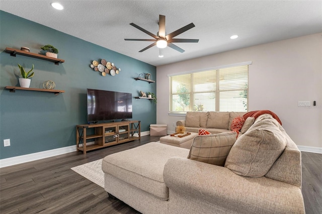 living room featuring ceiling fan, a textured ceiling, and dark wood-type flooring