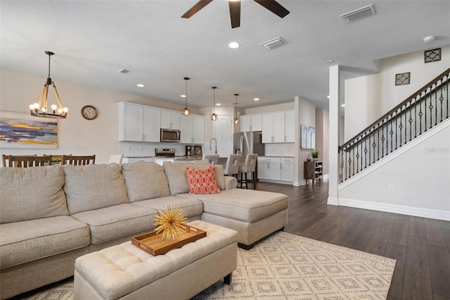 living room with wood-type flooring, a textured ceiling, and ceiling fan with notable chandelier