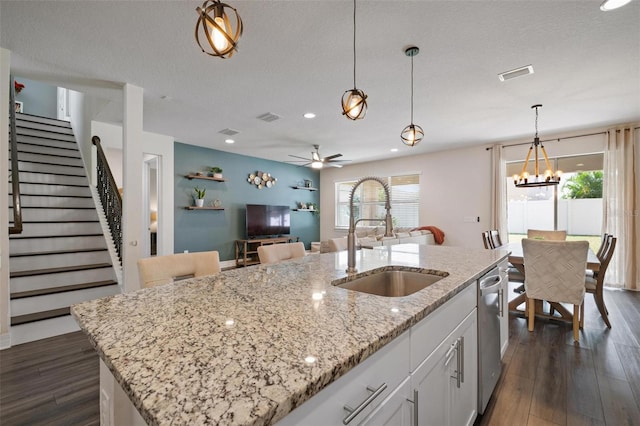 kitchen with hanging light fixtures, sink, a kitchen island with sink, white cabinetry, and ceiling fan with notable chandelier