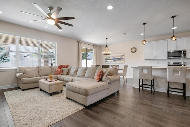 living room featuring ceiling fan with notable chandelier, a textured ceiling, and hardwood / wood-style flooring