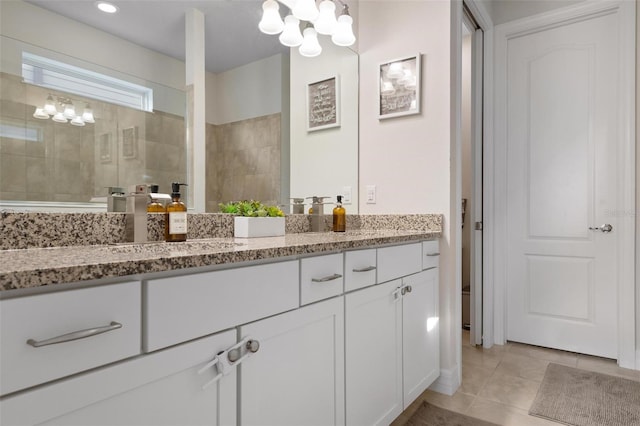 bathroom with tiled shower, vanity, and tile patterned flooring