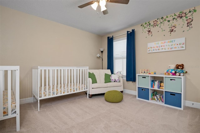 bedroom featuring ceiling fan, a nursery area, and carpet