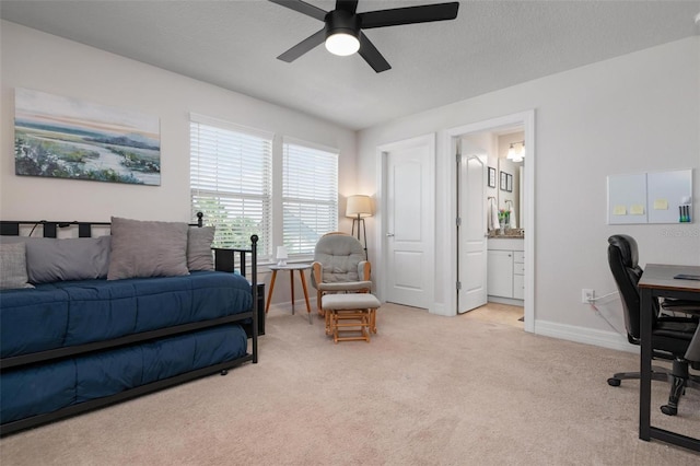 bedroom with ceiling fan, light colored carpet, and ensuite bathroom