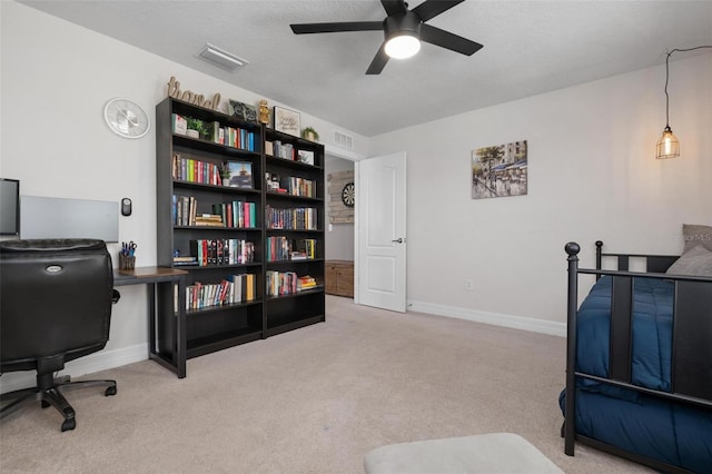 carpeted office space featuring ceiling fan and a textured ceiling