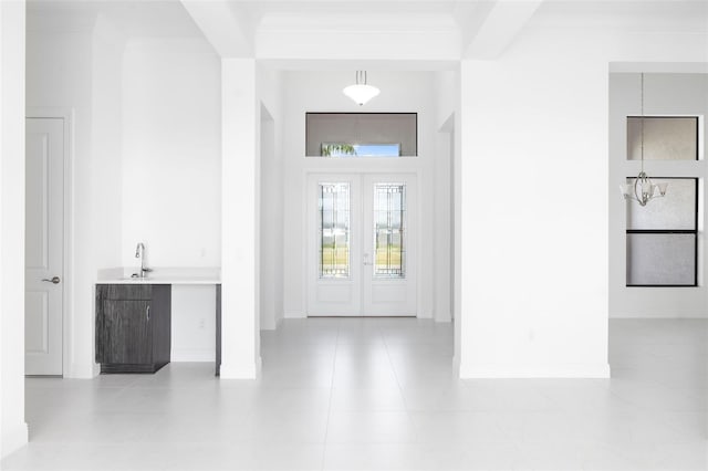 foyer entrance featuring crown molding, light tile patterned flooring, and sink