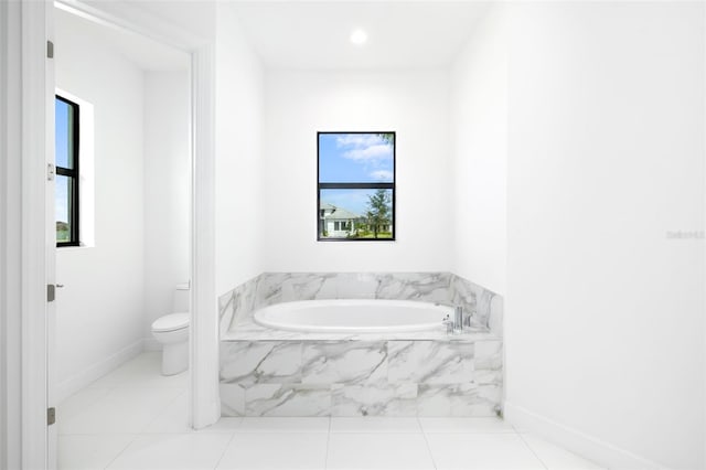 bathroom with tiled tub, toilet, and tile patterned flooring