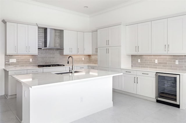 kitchen featuring a center island with sink, wall chimney range hood, wine cooler, and white cabinets