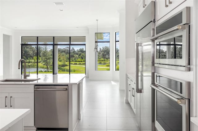 kitchen featuring appliances with stainless steel finishes, a healthy amount of sunlight, decorative light fixtures, and white cabinets