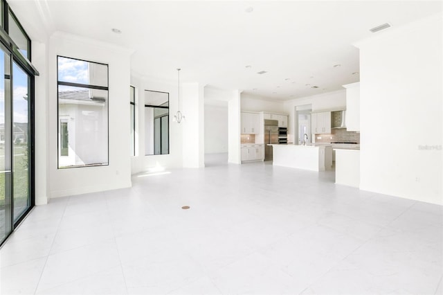 unfurnished living room with light tile patterned floors, crown molding, and sink