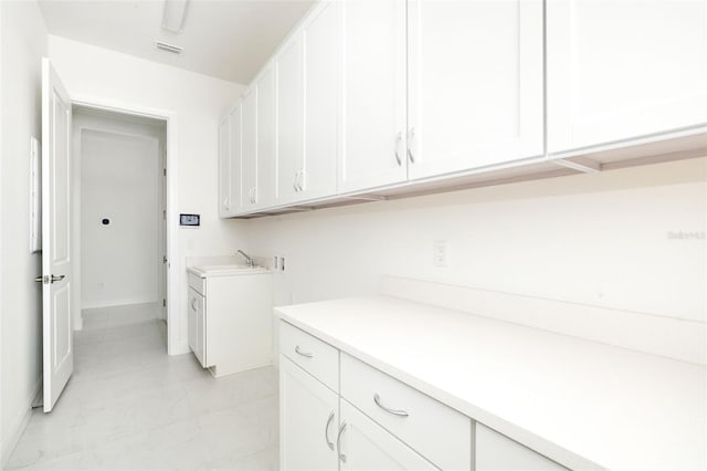 laundry area with hookup for a washing machine, cabinets, and sink