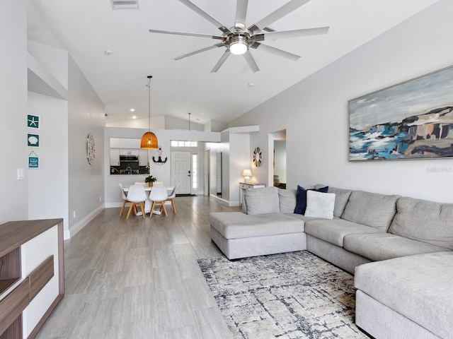 living room with ceiling fan, lofted ceiling, and light hardwood / wood-style floors