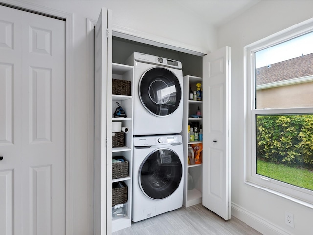 laundry area with stacked washer and dryer and light hardwood / wood-style floors