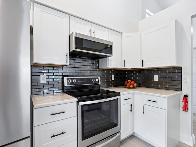 kitchen with appliances with stainless steel finishes, decorative backsplash, light hardwood / wood-style floors, and white cabinetry