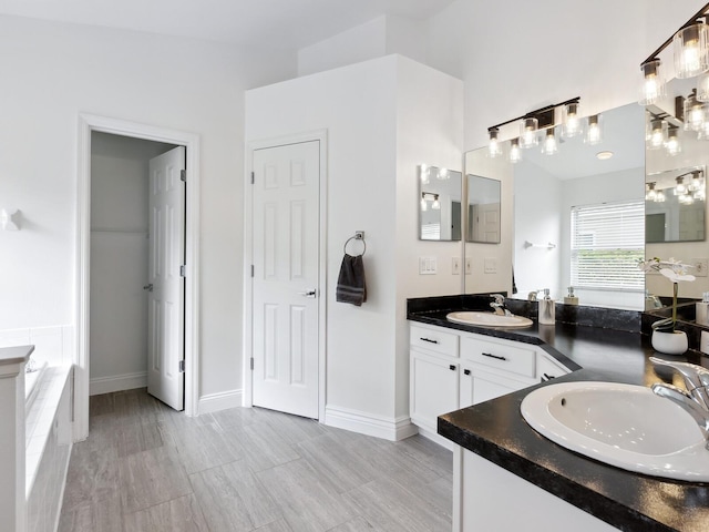 bathroom featuring vanity and tiled bath